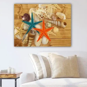 Canvastavla 70x100 cm - Två färgglada sjöstjärnor i orange och turkos bland snäckor på en träyta - Inredning & dekor Populär