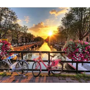 Canvastavla 70x100 cm - Två cyklar i en pittoresk kanalmiljö med blommor och solnedgång - Inredning & dekor Köp nu