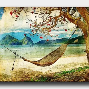 Canvastavla 70x100 cm - Avkopplande hängmatta hängande mellan trädgrenar vid en vacker strand med fjärran berg i bakgrunden - Inredning & dekor Kampanj