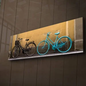 Beställ nu Canvastavla med LED-belysning 30x90 cm - Cyklar i kontrasterande färger mot en gul vägg Svart / Turkos / Gul - Inredning