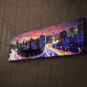 Canvastavla med LED-belysning 30x90 cm - Stadssilhuett vid skymning med ljusstrålar från vägarna Mörkblå / Orange / Lila - Inredning risnedsättning
