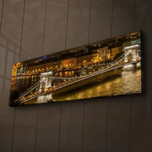 Sista chansen Canvastavla med LED-belysning 30x90 cm - Nattlig vy av en bro över en flod med upplysta byggnader i bakgrunden Guld / Blå / Svart - Inredning