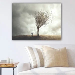 Canvastavla 70x100 cm - Ensam person står vid ett träd som tappar sina löv i en dramatisk och molnig himmel - Inredning & dekor Lägg i varukorgen